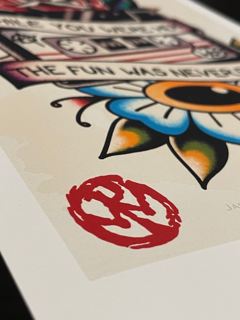 May include: A red and white illustration of a cassette tape with the text "While you were out the fun was never over" and a flower with a yellow eye. The image is framed and has a red stamp in the lower right corner.