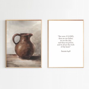 Puede incluir: Una pintura de acuarela de una jarra de barro marrón sobre una mesa de madera. La pintura está enmarcada en un marco de madera claro. El texto "But now, O LORD, thou art our father; we are the clay, and thou our potter; and we all are the work of thy hand." ISAIAH 64:8 está impreso en un fondo blanco en un marco separado.