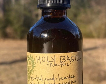 May include: A brown glass bottle with a dropper top and a paper label that reads "HOLY BASIL -Tincture-  purtis) used: leaves alwhol:1:2 -vodka Method: macerated 40 days & nights; shaken with love daily. 2oz. Sanctum"