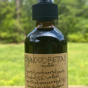 May include: A brown glass bottle with a dropper top and a paper label that reads "WOOD BETONY -tincture- parts) usefiaerial parts 19/who/21:2-vokal Method: macerated 40 wys nights; shalan  frunclis 2 oz"