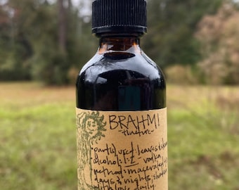 May include: A brown glass bottle with a black dropper top, containing a dark liquid. The label reads "Brahmi tincture" with handwritten details about the ingredients and method. The bottle is likely a herbal remedy or supplement.