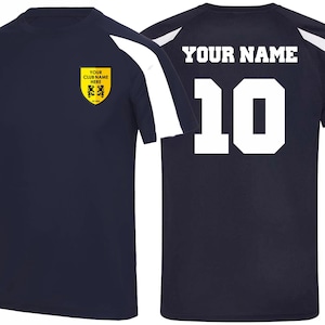 May include: Navy blue athletic jersey with white accents on the shoulders and sleeves. The front features a yellow crest with text and a logo. The back displays the number 10 and the text "YOUR NAME".