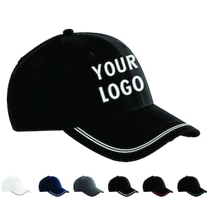 May include: Black baseball cap featuring the text "YOUR LOGO" in white. The cap has a curved peak with two white stripes. Other caps in white, navy blue, grey, and black are displayed below.
