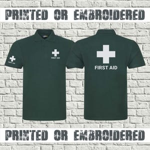 May include: Two dark green polo shirts with white "First Aid" crosses. One shirt has a cross on the left sleeve and chest, the other has a cross on the back. The text "PRINTED OR EMBROIDERED" is above and below the shirts.