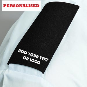 May include: A black fabric patch with the text "ADD YOUR TEXT OR LOGO" in white lettering. The patch is on a light blue garment. The word "PERSONALISED" is in red text at the top.