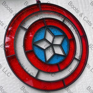 May include: A red, white, and blue circular ornament with a star in the center. The ornament is made of glass and has a glitter finish.