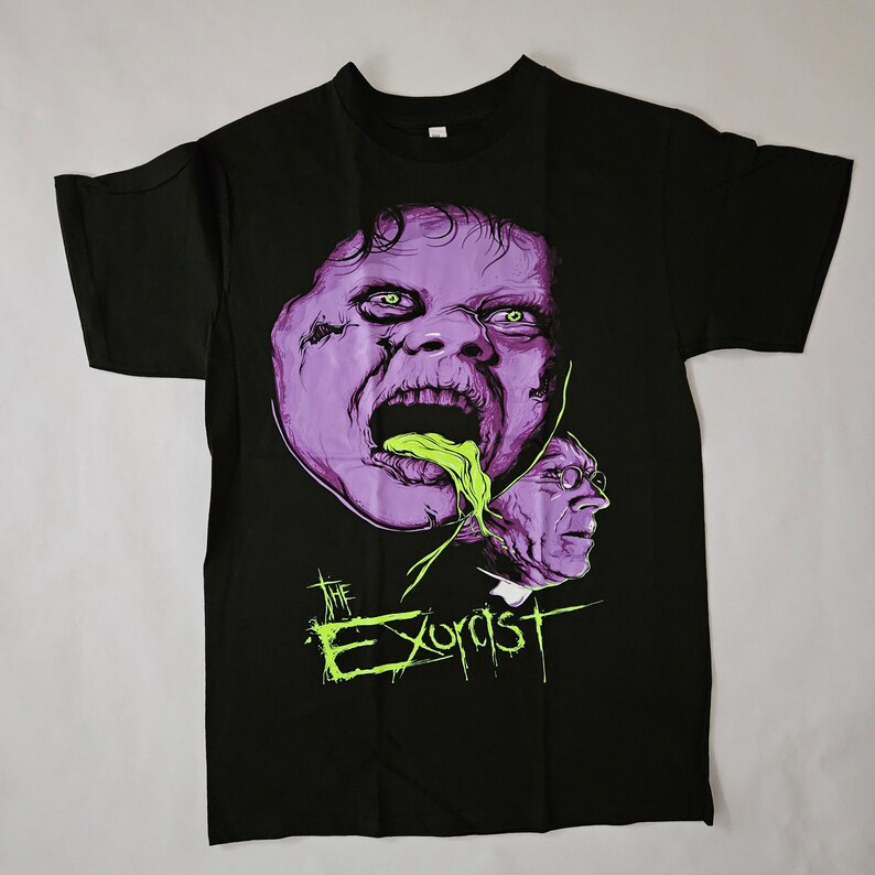 May include: Black t-shirt featuring a purple and green graphic of a demon from the film "The Exorcist".