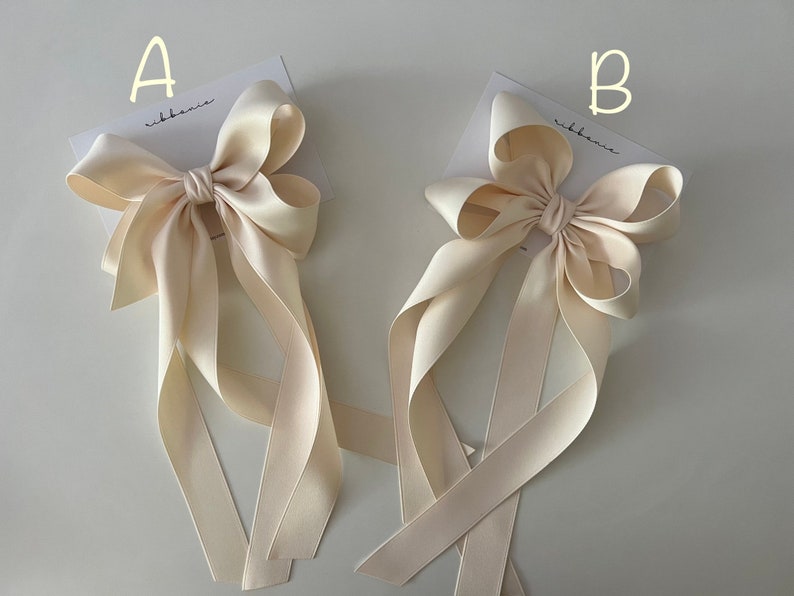 A large white satin wedding hair bow with long tails shown on a hair clip for a bride