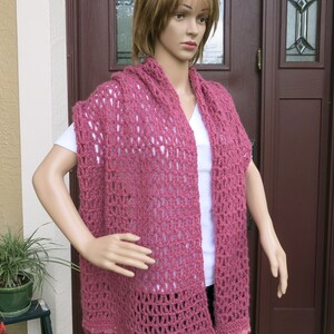 May include: A pink crocheted shawl with a lacy pattern and a scalloped edge.