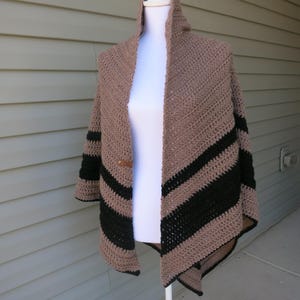 May include: A brown and black striped crochet shawl with a long, pointed shape. The shawl is draped over a white mannequin.