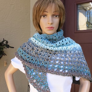 May include: A crocheted shawl with a gradient of blue, teal, and brown colors. The shawl is made with a delicate open stitch pattern.