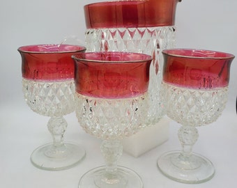 May include: A set of four vintage glass drinkware pieces in a cranberry red and clear diamond pattern. The set includes a pitcher and three glasses.