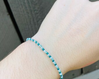 May include: A simple bracelet made with small white and teal beads.