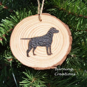 May include: A wood slice ornament with a black silhouette of a Labrador Retriever dog. The ornament is hanging from a twine string and has the text "Burning Creations" on the bottom.