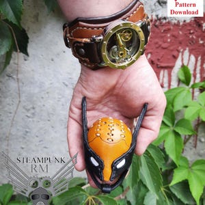 Puede incluir: Patrón de cuero steampunk para una máscara con un esquema de color negro y naranja. La máscara tiene un diseño cosido y un reloj de estilo steampunk se muestra en el fondo. La imagen incluye el texto "STEAMPUNK RM Leather patterns Digital goods".