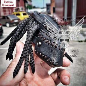 May include: A black leather mask with a braided rope attached. The mask has stitching details and a metal rivet. The mask is held in a hand. The image includes the text "STEAMPUNK RM" and "Leather patterns Digital goods".