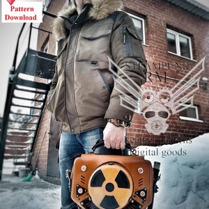 May include: A brown leather steampunk-style bag with a large, black and yellow radiation symbol on the front. The bag has a metal handle and a variety of metal accents. The bag is being held by a person wearing a brown jacket and blue jeans.