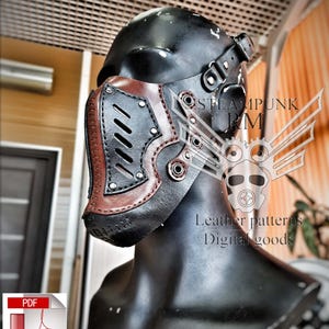 Könnte beinhalten: Eine braune und schwarze Leder-Steampunk-Maske mit einem Metallnasenschutz und Nieten. Die Maske befindet sich auf einem schwarzen Mannequin-Kopf. Der Text "STEAMPUNK RM" ist im Hintergrund sichtbar. Der Text "Leather patterns Digital goods" ist ebenfalls im Hintergrund sichtbar.