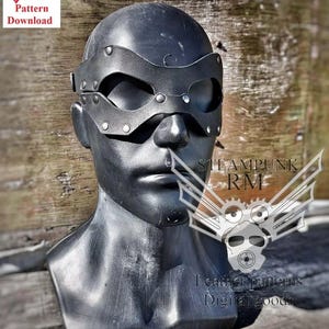 Op de afbeelding: Zwart leren masker met een steampunk-ontwerp. Het masker heeft een brede oogopening en is versierd met klinknagels. Het masker zit op een mannequinhoofd.