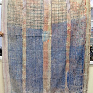 May include: A large, rectangular textile with a patchwork design. The colour palette includes blue, beige, and orange vertical stripes and a plaid pattern at the top. The textile has a worn, vintage appearance, with visible stitching throughout. The tag reads "VO1506".