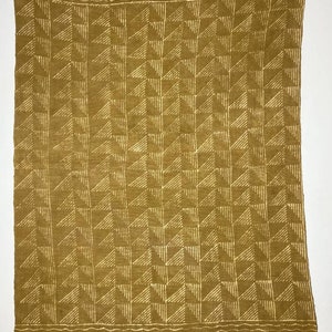 May include: A mustard yellow woven throw blanket with a geometric pattern of white triangles. The blanket has a fringe border.