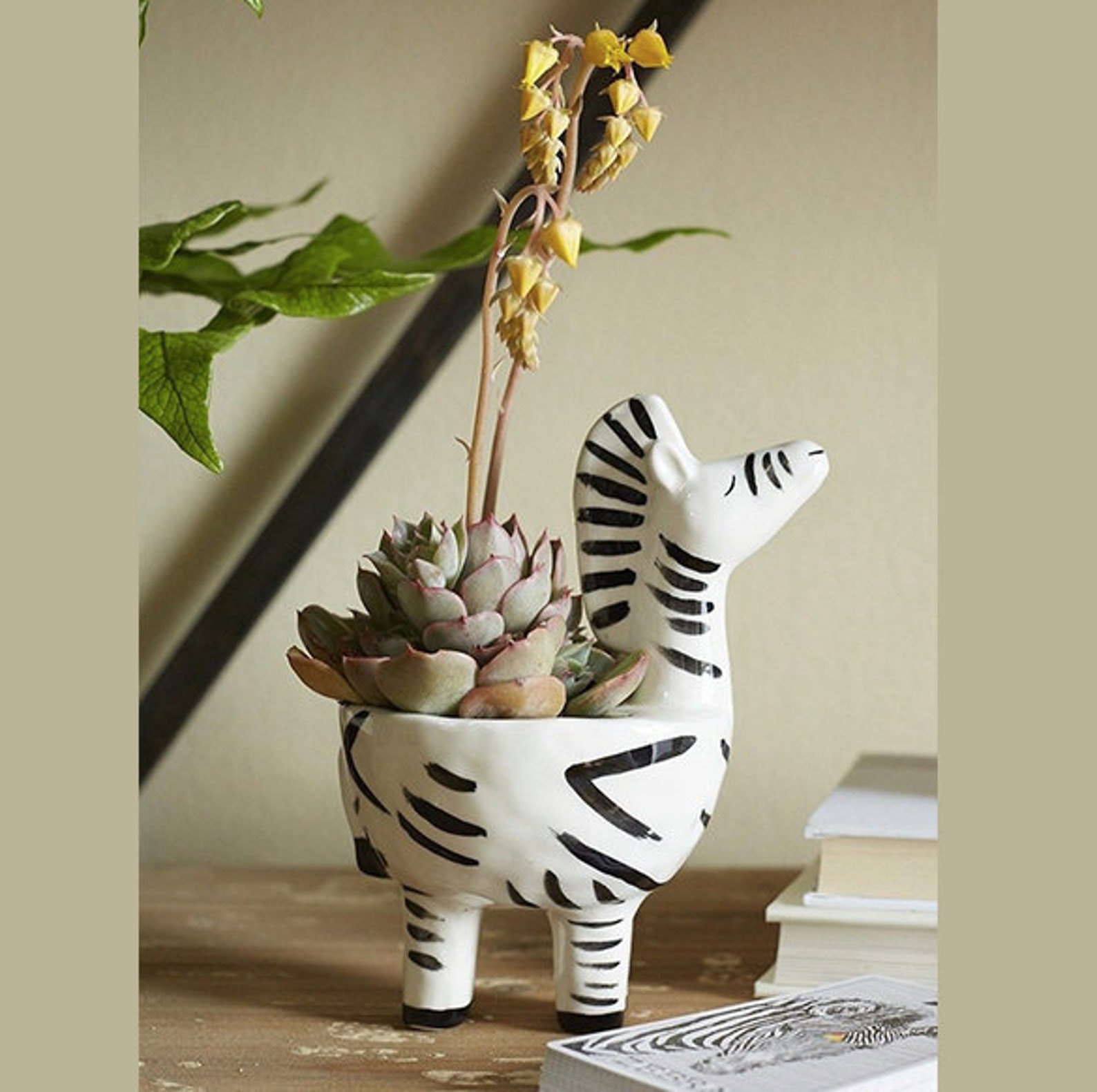 plant pot shaped like a white zebra.  fake plants inside of it.