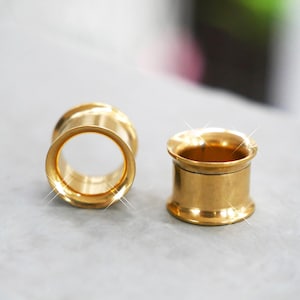 以下が含まれることがあります： 2つの金色のイヤーゲージ。ゲージは円筒形で、両端にフレアリムが付いています。ジュエリーは研磨された金属仕上げです。ゲージは、拡張された耳のピアスに着用するように設計されています。