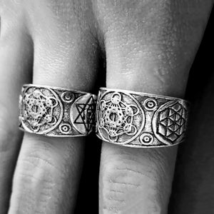 May include: Two silver rings with geometric designs. The rings feature a star, a circle, and a flower-like pattern.