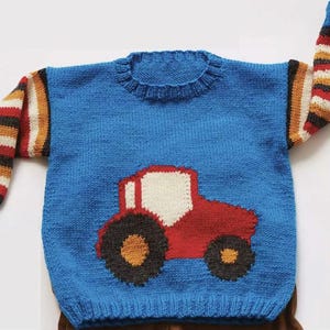 May include: A blue knit sweater with a red tractor applique on the front. The sleeves are striped with red, brown, tan, and white. The sweater has a ribbed neckline and cuffs.