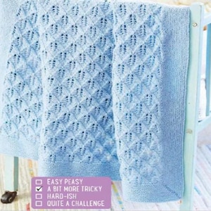 May include: A light blue knitted baby blanket with a diamond pattern and a ribbed border. The blanket is draped over a light blue crib. The text on the image says "A bit more tricky".
