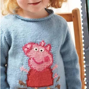 May include: A light blue knitted jumper with a pink pig design. The pig has a red body and is surrounded by brown and yellow details. The jumper is worn by a young child.