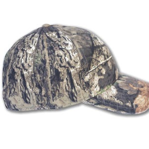 May include: A camouflage baseball cap with a curved brim. The cap features a pattern of brown, green, and tan, resembling tree bark. The cap is designed for outdoor activities.