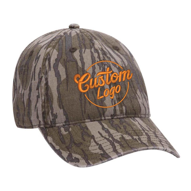 Puede incluir: Una gorra de b&eacute;isbol de camuflaje con un logotipo circular bordado en naranja que dice "Custom Logo".