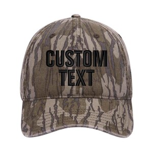 Puede incluir: Una gorra de b&eacute;isbol de camuflaje con texto bordado en negro que dice "CUSTOM TEXT".