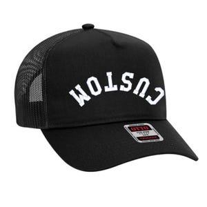 May include: Black trucker hat with a white "CUSTOM" embroidered on the front in an arched design. The hat has a black mesh back and a red and white "OTTO" label.