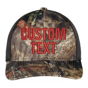 May include: A black and brown camouflage trucker hat with a red embroidered "CUSTOM TEXT" on the front.