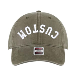 Puede incluir: Gorra verde oliva con la palabra "CUSTOM" bordada en letras blancas en la parte delantera. La gorra tiene una visera curva y una correa ajustable. Una pequeña etiqueta es visible en la visera.