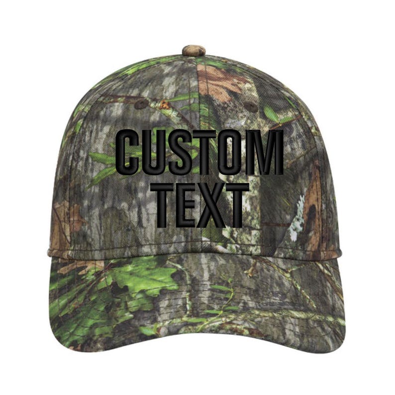 May include: A camouflage baseball cap with the words "CUSTOM TEXT" embroidered in black. The cap features a curved brim and a button on top. The camouflage pattern includes shades of green, brown, and tan.