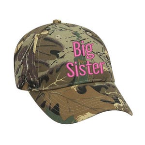 May include: Camouflage baseball cap with the words "Big Sister" embroidered in pink.