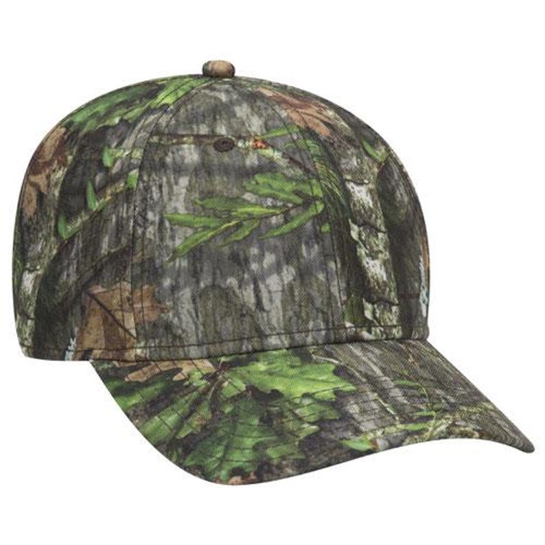 May include: A camouflage baseball cap with a curved brim. The cap features a pattern of green leaves, brown branches, and gray bark, creating a woodland camouflage design. The cap has a button on top.