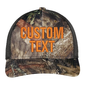 May include: A black and camouflage trucker hat with orange embroidered text that says "CUSTOM TEXT".