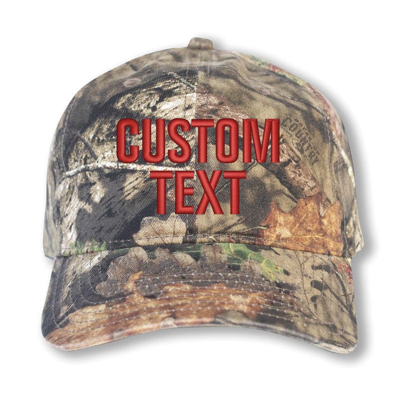 May include: A camouflage baseball cap with the words "CUSTOM TEXT" embroidered in red. The cap features a curved brim and a classic six-panel design, perfect for outdoor activities.