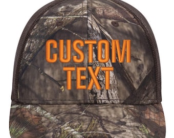 May include: A brown and orange camouflage trucker hat with a black mesh back. The hat has the text "CUSTOM TEXT" embroidered in orange on the front.