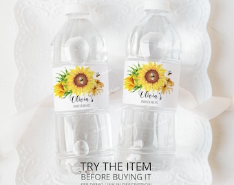 May include: Two clear plastic water bottles with labels featuring a sunflower and bee design. The labels say "Olivia's Birthday".