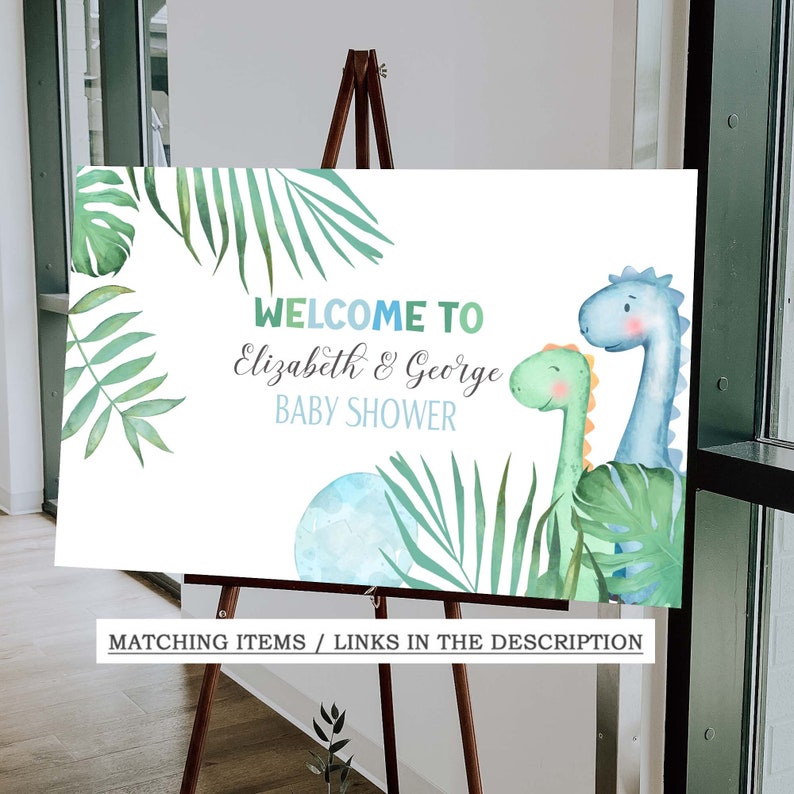 May include: Welcome to Elizabeth & George Baby Shower sign with a blue and green dinosaur illustration and tropical leaves.