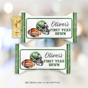 Puede incluir: Dos envoltorios blancos de barra de caramelo con ribete verde y el texto "Oliver's First Year Down". Cada envoltorio presenta un diseño de fútbol y casco de acuarela. Un trozo de golosina de arroz crujiente es visible en el lado izquierdo. La parte inferior de la imagen dice "VER ENLACE DE DEMOSTRACIÓN EN LA DESCRIPCIÓN."