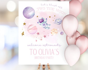 May include: Pink and purple welcome sign with a watercolor astronaut, planets, and stars. The sign says "Let's blast off to the moon" and "Welcome astronauts to Olivia's birthday party".