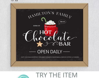 May include: A framed sign with a black chalkboard background. The sign reads "Hamilton's Family Hot Chocolate Bar" with a red mug graphic. The sign is 10" x 8" and has a brown frame. The sign also says "Open Daily".