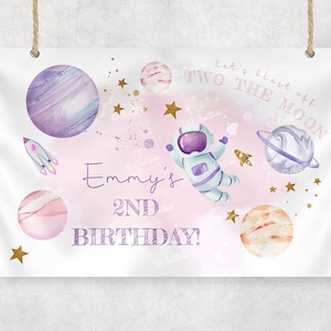 Peut inclure: Une bannière d'anniversaire rose et blanche sur le thème de l'espace. Elle représente un astronaute, des planètes, des étoiles et le texte "Let's blast off to the moon, Emmy's 2nd Birthday!"