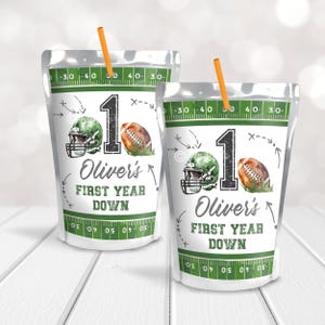 May include: Two clear pouches with orange straws, featuring a football theme. Each pouch has a green football helmet, a football, and the text "1 Oliver's FIRST YEAR DOWN" on a white background with a green football field design.